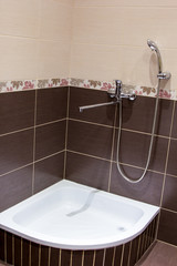 shower tray in the bathroom lined with brown tiles