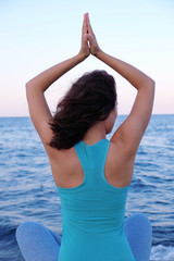 Fototapeta na wymiar Young woman practicing yoga at seashore