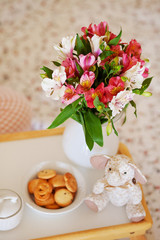 table with colorful flowers in a vase, cookies and toys
