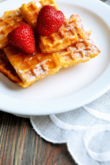 Sweet homemade waffles with strawberries  on plate, on table background