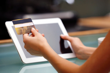 Female hands holding credit card with digital tablet on table close up