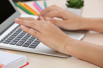 Woman using laptop on workplace close up