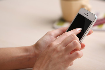 Woman using mobile phone on workplace close up