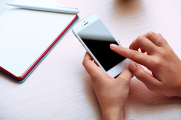 Woman using mobile phone on workplace close up