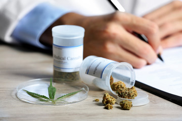 Doctor writing on prescription blank and bottle with medical cannabis on table close up - obrazy, fototapety, plakaty