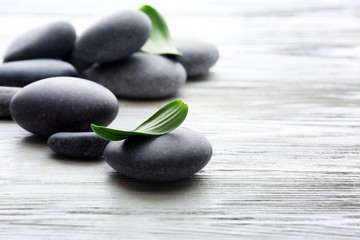 Spa stones with green leaves on wooden background