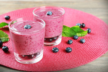 Glasses of blueberry smoothie on pink mat, closeup