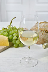 Still life of wine, grape, cheese and bread on light background
