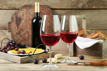 Still life of wine, grape, cheese and bread on rustic wooden background