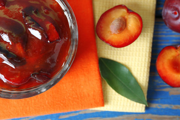 Tasty homemade plum jam in glass saucer on colorful napkins, top view