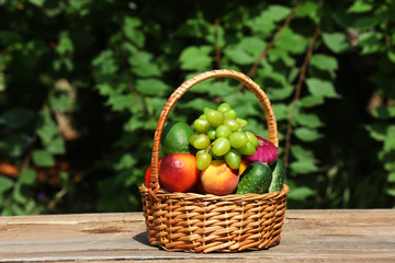Heap of fresh fruits and vegetables in basket on table outdoors