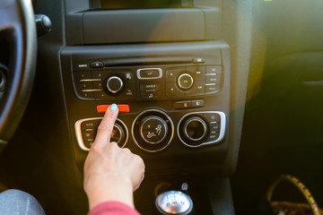 Female driver pressing a red hazard button