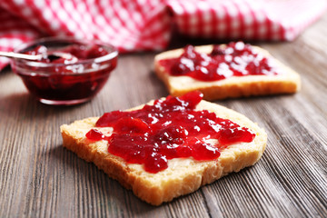 Bread with butter and homemade jam on wooden table, closeup