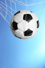 Soccer ball in the net on blue background