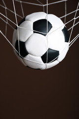 Soccer ball in the net on brown background