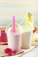 Plastic cup of milkshake on light wooden background