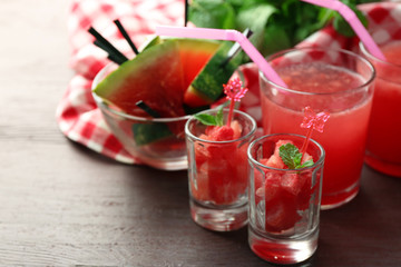 Cold watermelon desserts and drinks in glasses, on wooden table background