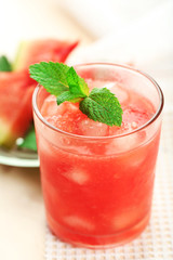 Cold watermelon drinks in glasses, on wooden table background