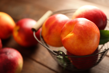 Fresh peaches in wicker basket on wooden background