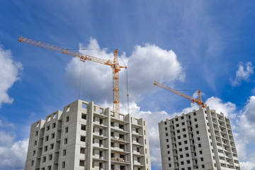 Fototapeta premium Multi-storey houses under construction and high-rise crane