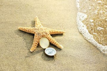 Fototapeta na wymiar Compass with sea star on sand beach background