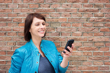 Smiling older woman reading text on cell phone