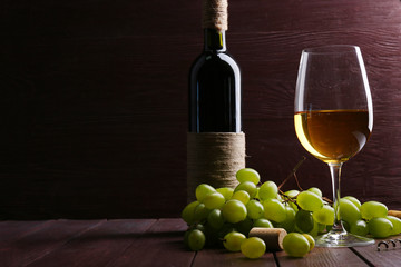 Obraz premium Bottle and glass of wine with grape on wooden background