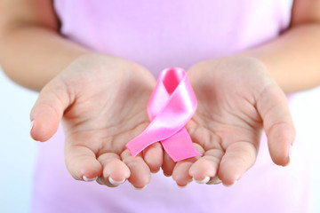 Pink ribbon in woman's hands close up