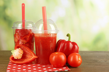 Red vegetable and fruit salad and healthy fresh drink in plastic cups on wooden background. Colorful diet concept