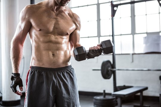 Fit man lifting heavy black dumbbell