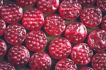 Pile of tasty delicious raspberry hard candy lying on wooden