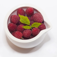 Ripe raspberry with leaf in a bowl