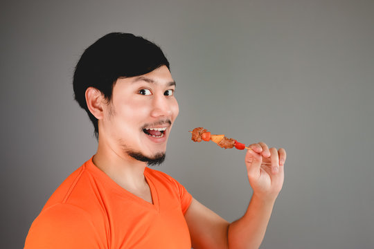 Asian Man Is Eating BBQ Skewers.