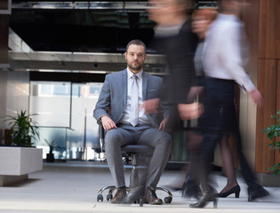 business man sitting in office chair, people group  passing by