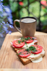 Morning breakfast sanwiches with a cup of coffee on a wooden cut