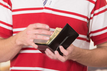 Man wearing red white striped shirt holding wallet with money