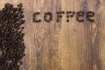 Whole aromatic coffee beans on a wooden background closeup