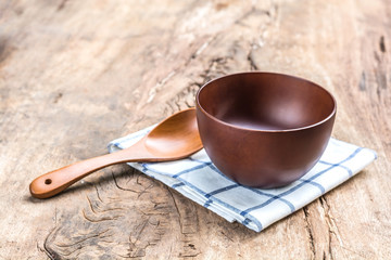 bowl with spoon and dishcloth on old wooden table