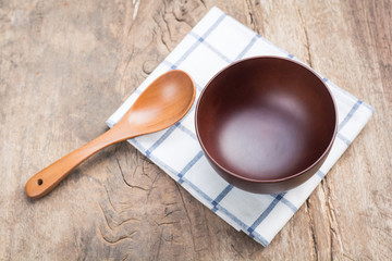 bowl with spoon and dishcloth on old wooden table