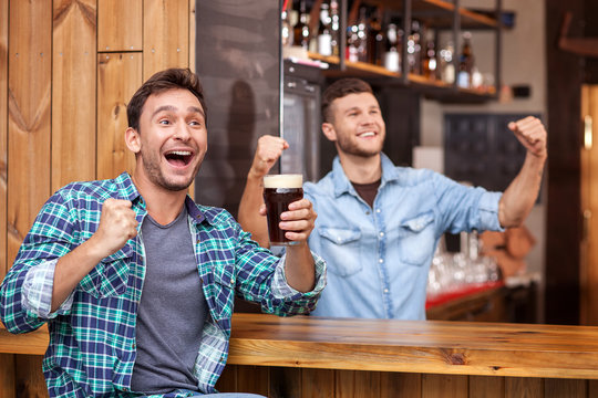 Cheerful young guy and bartender in sport pub