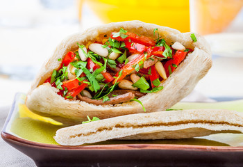 Pita bread with meat, parsley, tomato, bell pepper and pine seeds
