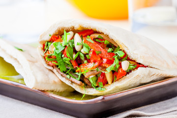 Pita bread with meat, parsley, tomato, bell pepper and pine seeds