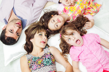 Adorable hispanic family lying down with heads touching showing