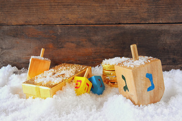 image of jewish holiday Hanukkah with wooden colorful dreidels (spinning top) and chocolate traditional coins over december snow   © tomertu
