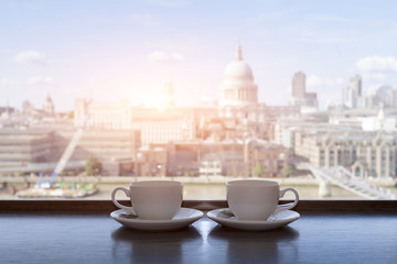 Two cups of coffee with panoramic view of a city in background
