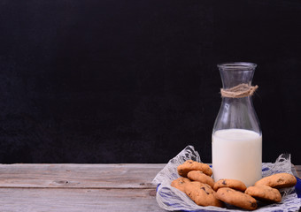 Bottle of milk with cookies on rustic table