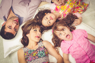 Young adorable hispanic sisters and parents lying down with