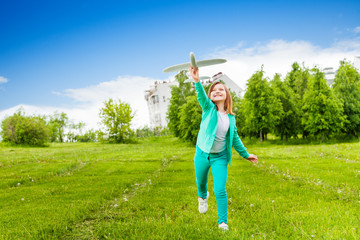 Looking girl holds airplane toy with one leg up