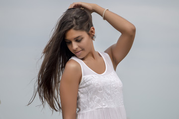 Fototapeta premium Close view of a beautiful woman on a white dress over a blue sky.