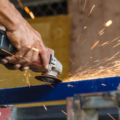 Electric wheel grinding on steel structure in factory